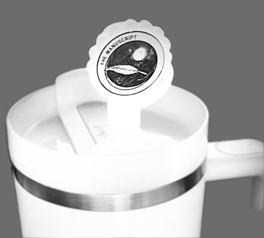 The white Stanley tumbler has a lid adorned with a round sticker featuring a celestial design and "The Manuscript" text on a solid gray background. Pair it with Kreative Kreationz's silicone straw covers, fitting 10mm straws for Stanley cup sizes 40oz, 30oz, and 20oz.