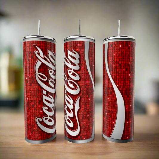 Three Cola 20oz Skinny Tumblers by Kreative Kreationz, featuring red designs with white logos and a sparkling sequin-style background, stand on a wooden surface—ideal as stylish, eco-friendly drinkware alternatives.