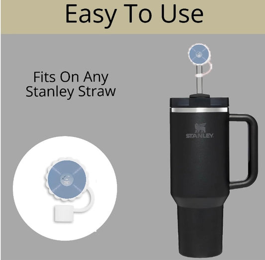 A black Stanley tumbler with a handle and straw features the Taylor Swift Straw Topper by Kreative Kreationz, shown as a blue silicone cap on the straw. Text reads "Easy To Use" and "Fits On Any Stanley Straw," with an inset close-up of the topper.