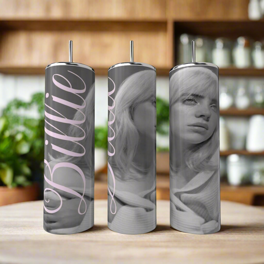 Three Kreative Kreationz Billie Ellish 20oz Tumblers, featuring black-and-white portraits of a woman and "Billie" script, sit on a wooden table. These eco-friendly, reusable tumblers add style and sustainability to your collection.