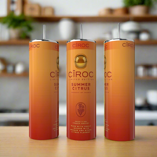 Three tall, slender Kreative Kreationz Summer Citrus 20oz Tumblers with eco-friendly stainless steel straws are displayed on a wooden surface. The orange and gold gradient tumblers stand out against a blurred kitchen background.