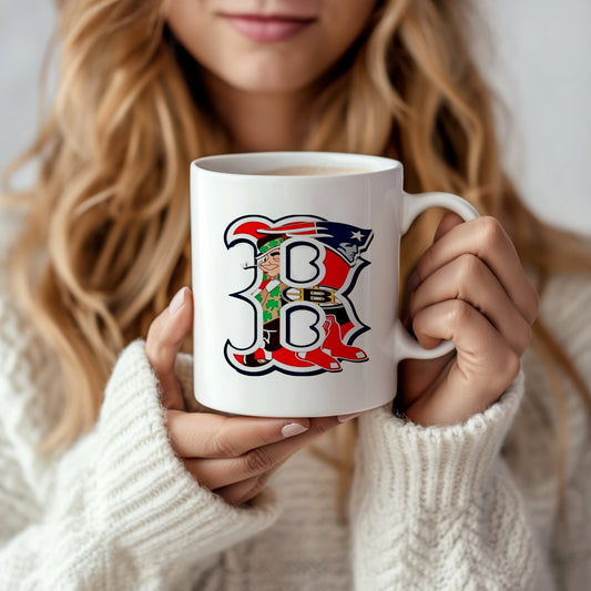A woman with wavy blonde hair in a white sweater holds the Boston Ceramic Mug by Kreative Kreationz, featuring a large, ornate letter "B" decorated with Boston Bruins-inspired patriotic and camouflage patterns.