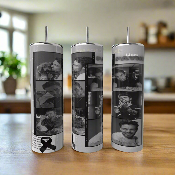 Set of three One Direction 20oz tumblers by Kreative Kreationz, featuring black-and-white collage panels of a smiling man, with one sublimated tumbler accented by a black ribbon and text. Background is a blurred kitchen scene.