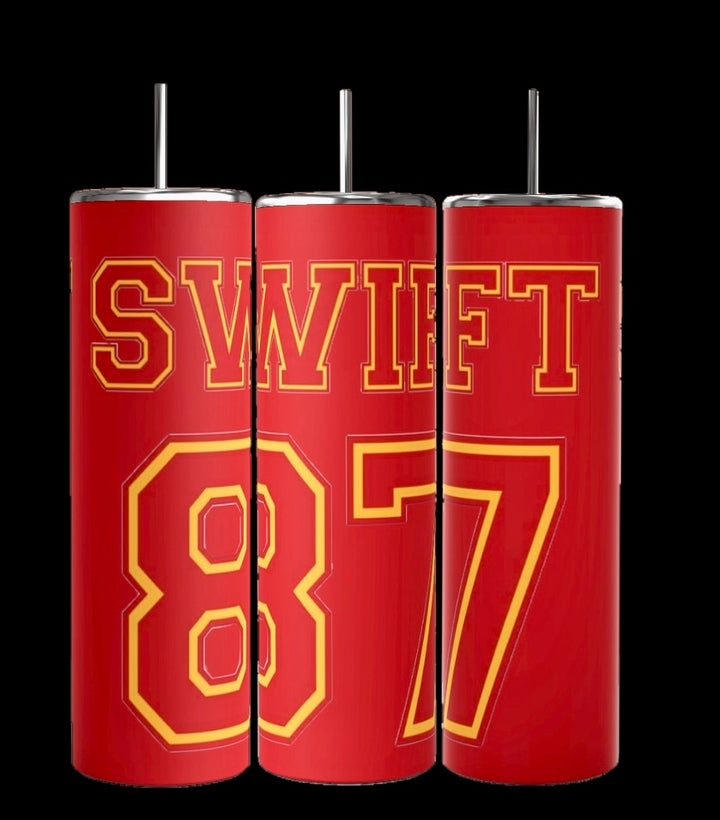 The Taylor Swift | 87 Chiefs 20oz Skinny Tumbler by Kreative Kreationz features three red tumblers with metallic straws, each showcasing bold yellow text: one reads "SW," another "IFT," and the last shows "87." The stainless steel design mimics a sports jersey, adding a sleek touch to your drinkware collection.