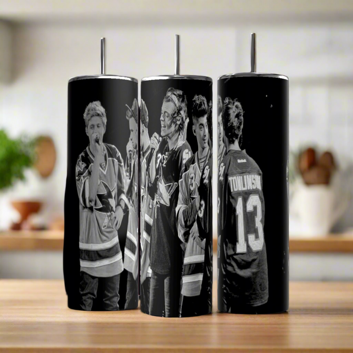 Three Kreative Kreationz One Direction B&W 20oz Stainless Steel Tumblers, featuring black-and-white images of people in hockey jerseys (including "TOMLINSON 13"), are displayed side-by-side on a wooden surface.