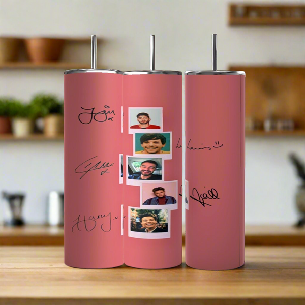 Three Kreative Kreationz One Direction Pink 20oz Stainless Steel Tumblers, each with black signatures and smiling group photos, are arranged side by side on a wooden kitchen surface.