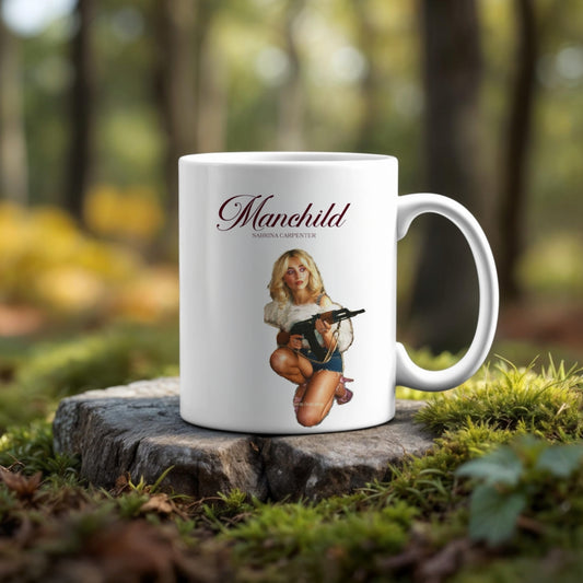 The Manchild Ceramic Mug 20oz Tumbler by Kreative Kreationz sits on a tree stump, showcasing a woman in a fur coat with a toy gun and "Manchild" and "Sabrina Carpenter" above, set against a blurred forest backdrop.