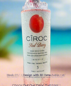 Two cans of Kreative Kreationz Ciroc 20oz Tumbler with 3D Lid Topper are shown on a wooden surface, reminiscent of travel tumblers. The left can is Red Berry flavor, topped with ice and a cherry. The right can is Vodka Snap Frost flavor, topped with ice and a lemon slice. Both cans feature product information and branding.