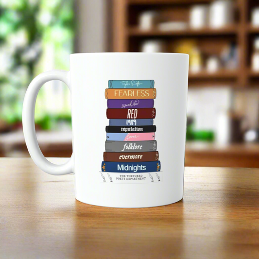 The Taylor Swift Era’ Book Ceramic Mug by Kreative Kreationz features vibrant book spines titled after Taylor Swift albums, making it a perfect gift for any Swiftie. The eye-catching design stands out in any kitchen.