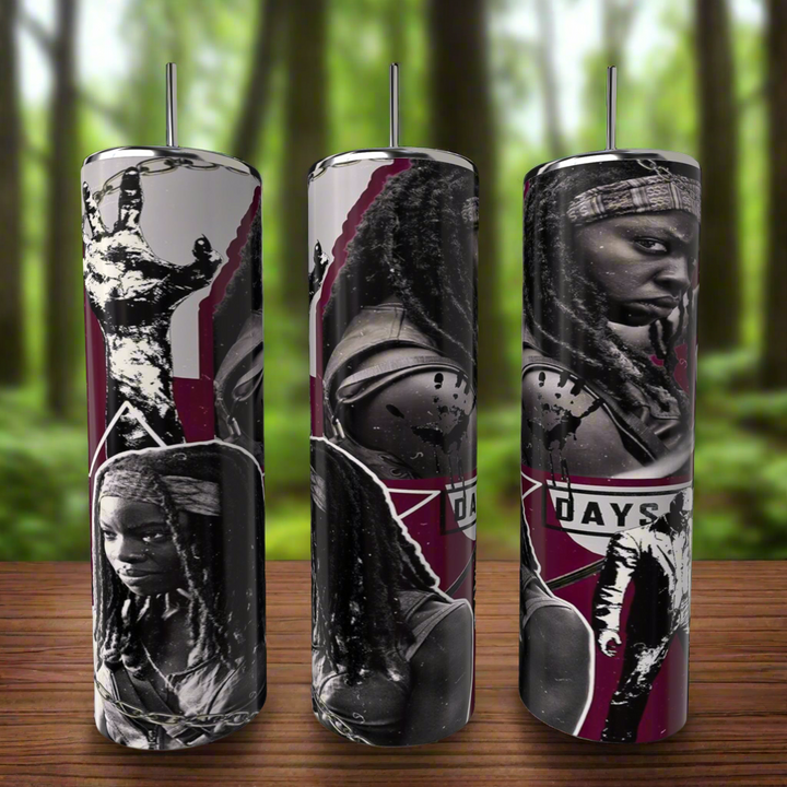 Three cylindrical candles feature black and white images of a person holding a sword against a maroon backdrop, echoing The Walking Dead Tumbler series. They rest on a wooden surface with a blurred forest background. Product: The Walking Dead | Michone | 20oz Skinny Tumbler by Kreative Kreationz.
