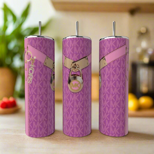 Three tall Kreative Kreationz MK 20oz Tumblers in pink with metal straws sit on a kitchen counter. Each features a pink and gold MK pattern with lock and keychain charms. The softly blurred background highlights the luxury drinkware.