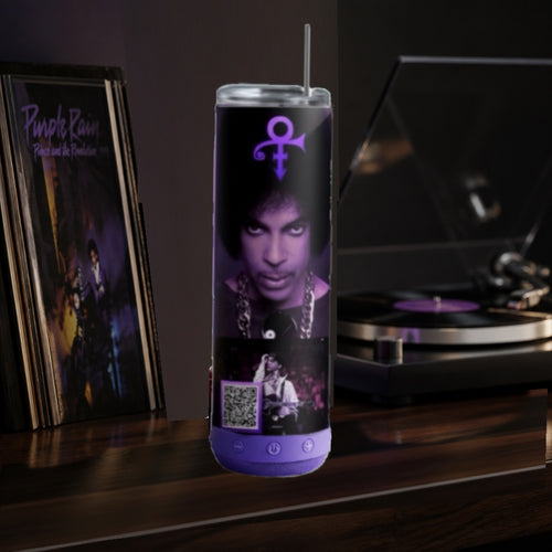 Tumbler with a bluetooth speaker with Prince on it, photo,and turntable on a dark surface with records and a turntable in the background