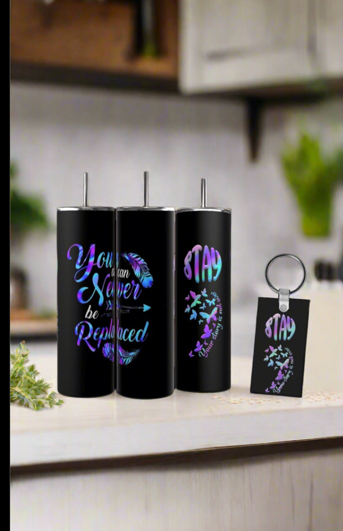 Three black tumblers with feather, arrow, and inspirational quotes, plus a “STAY” butterfly keychain, from Kreative Kreationz's Suicide Awareness Gift Set, sit on the counter—an uplifting reminder of hope.