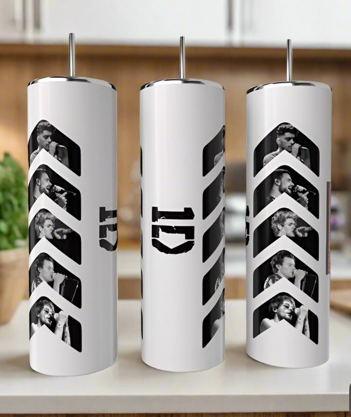 Three Kreative Kreationz 1D Play 20oz Tumblers with metal straws, each featuring black and white singing photos and a bold number 5 design, are lined up on a counter with a green plant in the background. Keeps drinks hot or cold.