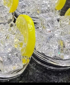 Two cans of Kreative Kreationz Ciroc 20oz Tumbler with 3D Lid Topper are shown on a wooden surface, reminiscent of travel tumblers. The left can is Red Berry flavor, topped with ice and a cherry. The right can is Vodka Snap Frost flavor, topped with ice and a lemon slice. Both cans feature product information and branding.