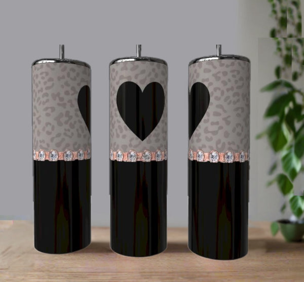 Three black and gray Kreative Kreationz Heart Rhinestone 20oz Skinny Tumblers feature leopard print bands, a heart design on the center tumbler, and faux gemstones, displayed on a wooden surface with a plant in the background.