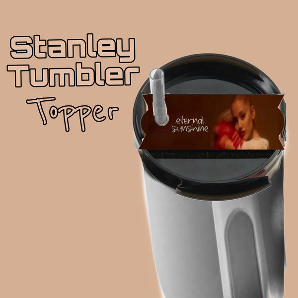 A Kreative Kreationz Ariana Grande Eternal Sunshine Stanley Lid Topper with a sepia-toned image and red accent fits your stainless steel Stanley tumbler with a clear straw. Text: "Stanley Tumbler Topper" and "eternal sunshine.